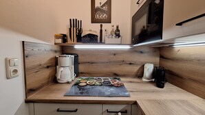 Eine kleine Küche mit Kaffeemaschine, Mikrowelle und einem Regal mit Gewürzen.