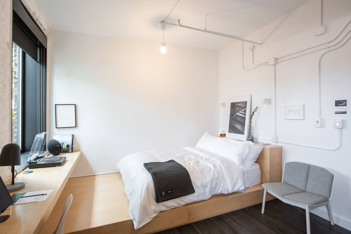 Een moderne slaapkamer met een bed, bureau, stoel en kunstwerken aan de muren.