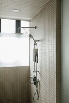 Een moderne badkamer met een douche, betegelde wanden en een raam.