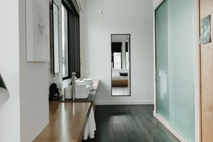 Een moderne badkamer met een houten wastafelmeubel, een grote spiegel en een douchecabine van glas.