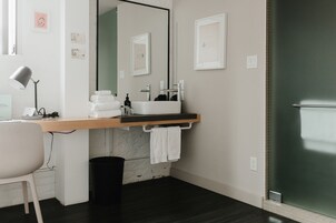Een moderne badkamer met een wit wastafelblad, spiegel en houten opbergmeubel.