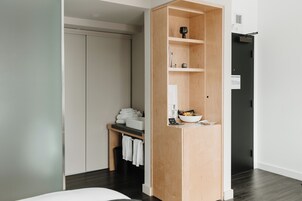 Een moderne badkamer met een houten wastafelmeubel, een handdoekrek en een klein plankje met toiletartikelen.