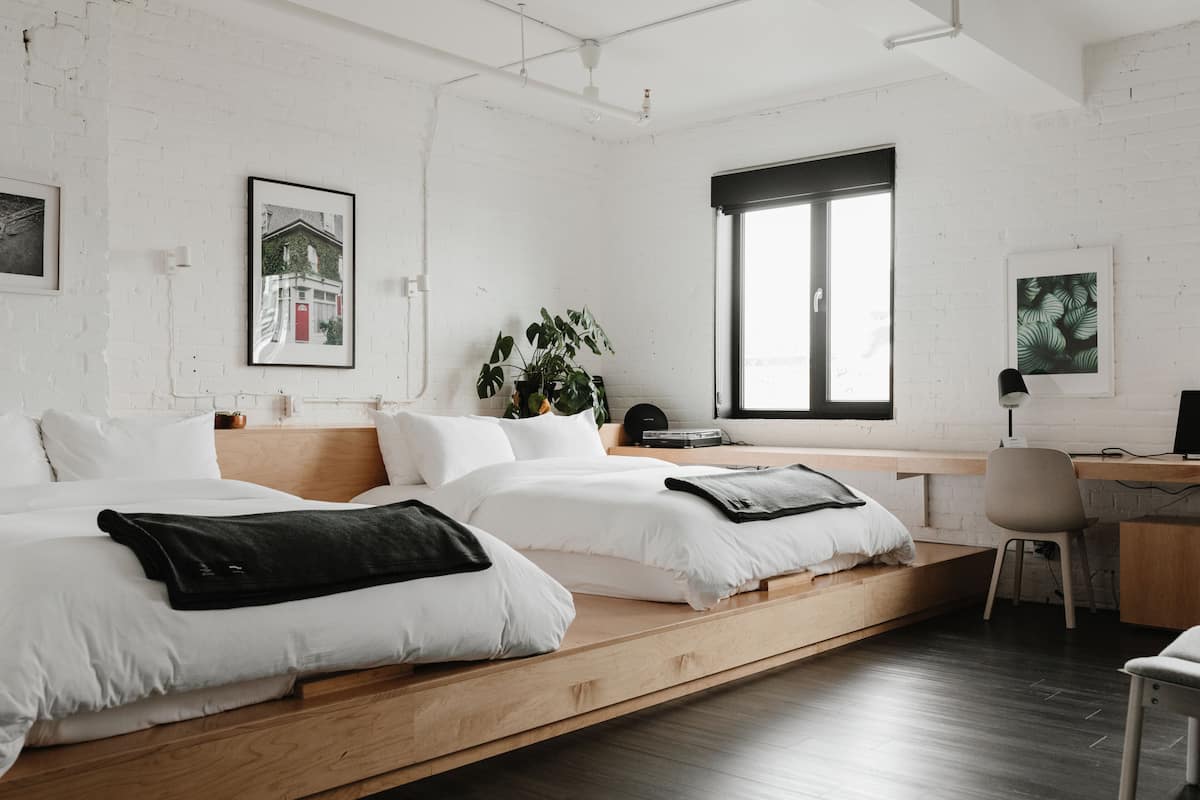 Een moderne slaapkamer met twee bedden, een bureau en een groot raam.