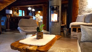 A cozy living room with a stone fireplace, a wooden coffee table, a comfortable sofa, and a chair.
