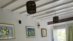 Una habitación con dos camas, una mesita, una lámpara en la pared y una puerta que da al exterior.