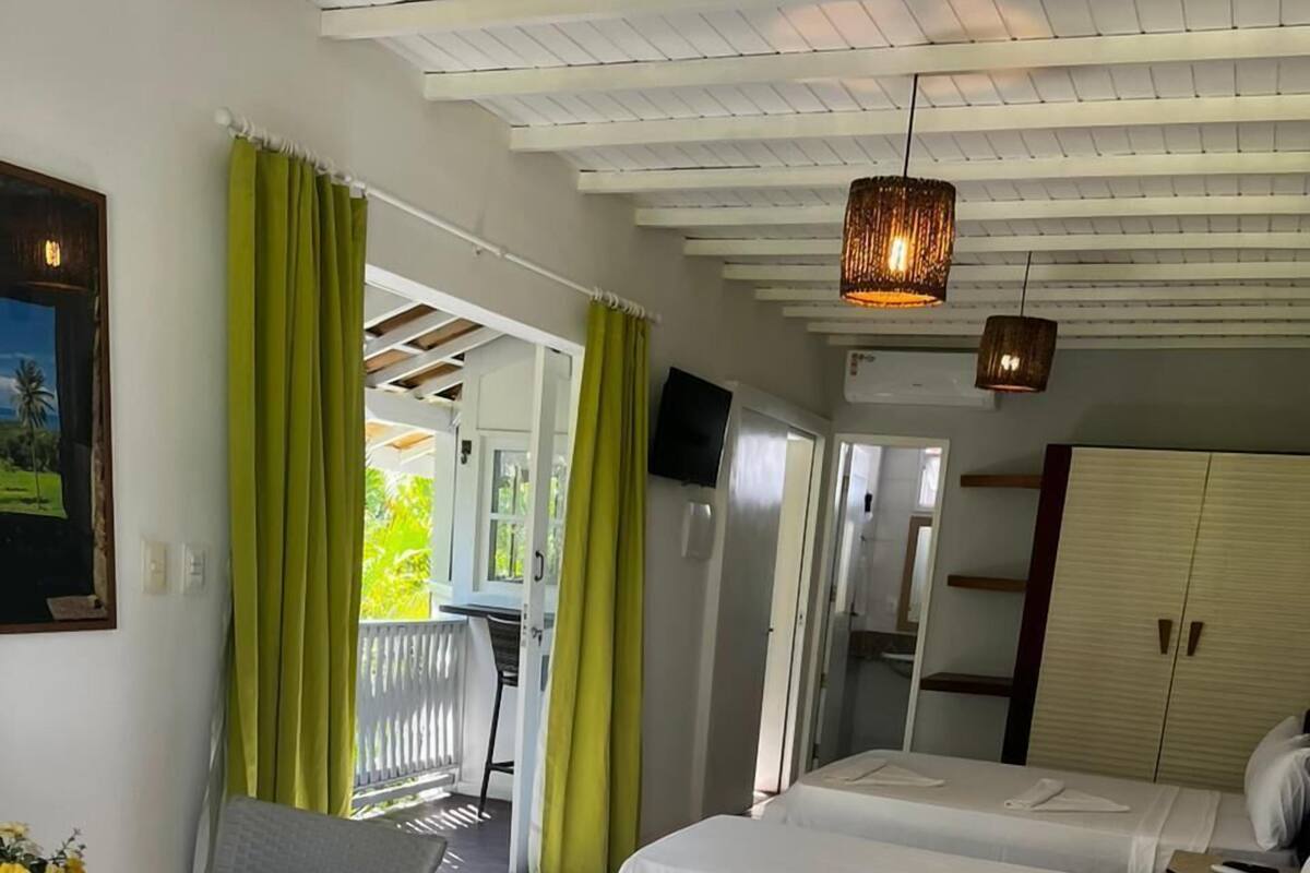 A room with two beds, a wooden table, a chair, a wardrobe, and a television.
