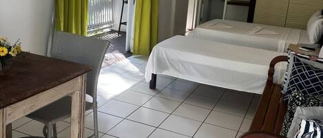 A room with two beds, a wooden table, a chair, a wardrobe, and a television.