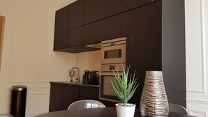 Une cuisine moderne avec des meubles de couleur sombre, une hotte de cuisinière en acier inoxydable et une machine à café.