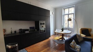 Une cuisine moderne avec des meubles de couleur noire, un four encastré et un coin repas comprenant une table ronde et des chaises.