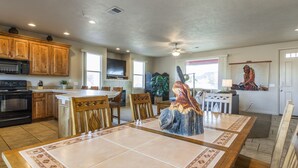 Una cocina amplia con armarios de madera, una isla central y un comedor con una mesa grande y sillas.