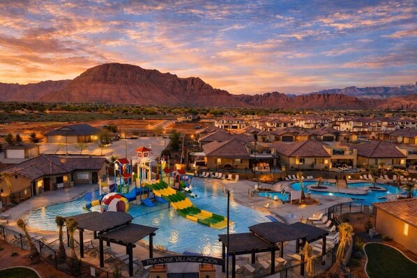 A resort with multiple swimming pools, a water park, and a mountainous backdrop.
