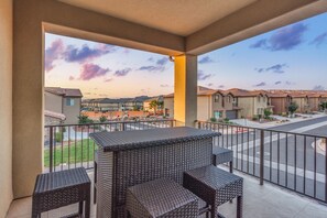 A balcony with wicker furniture and a view of a residential area.