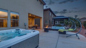 Ein Whirlpool, Sitzgelegenheiten im Freien und eine Pergola in einem Garten.