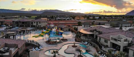 A resort with multiple swimming pools, a water park, and a mountainous backdrop.