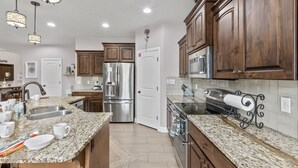 Una cocina moderna con encimeras de granito, electrodomésticos de acero inoxidable y armarios de madera.
