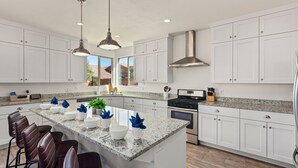 A modern kitchen with white cabinets, a granite countertop, and a central island with bar stools. - 94 PV, Luxury Home with Private Pool & Hot Tub, Fire Pit, Huge Kitchen, and More! (Santa Clara)