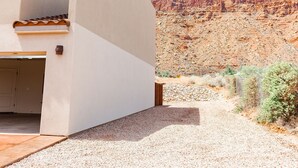 Un bâtiment moderne doté d’un toit plat et d’une petite fenêtre, se dressant au milieu d’un paysage désertique parsemé de collines rocheuses.
