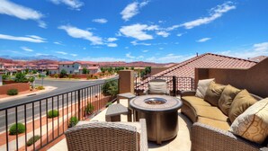 Una terrazza sul tetto con arredi da esterno, un braciere e vista su una zona residenziale con montagne sullo sfondo.