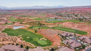 Un parcours de golf doté de plusieurs greens et de nombreux bunkers, entouré de zones résidentielles et bordé par des montagnes lointaines.