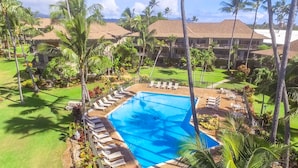 Un complexe hôtelier doté d’une piscine, entourée de chaises longues et de palmiers.