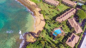 Vue aérienne d’un complexe hôtelier comprenant une plage, une piscine et plusieurs bâtiments.