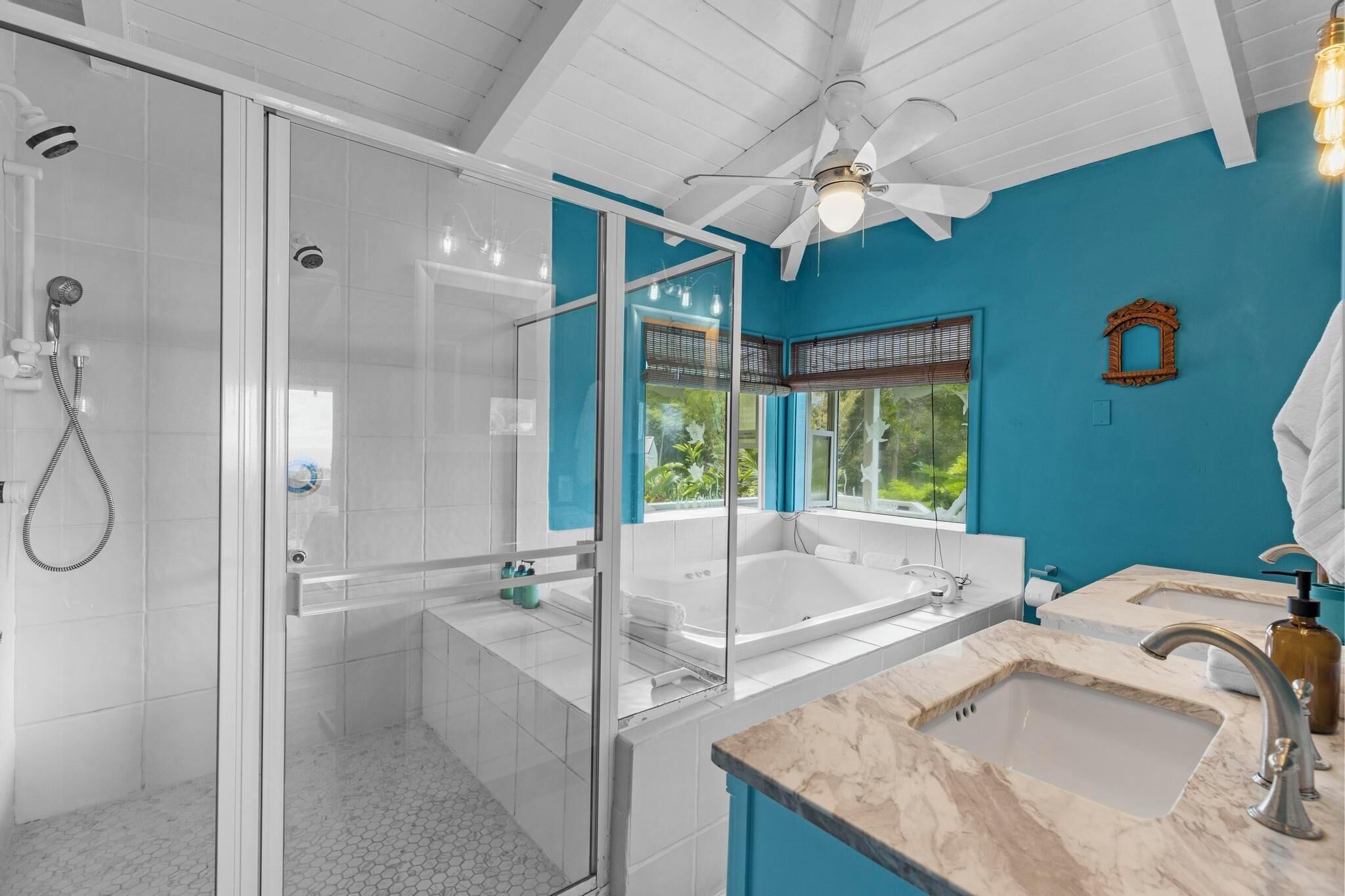 A modern bathroom with a glass-enclosed shower, a large bathtub, and two sinks.