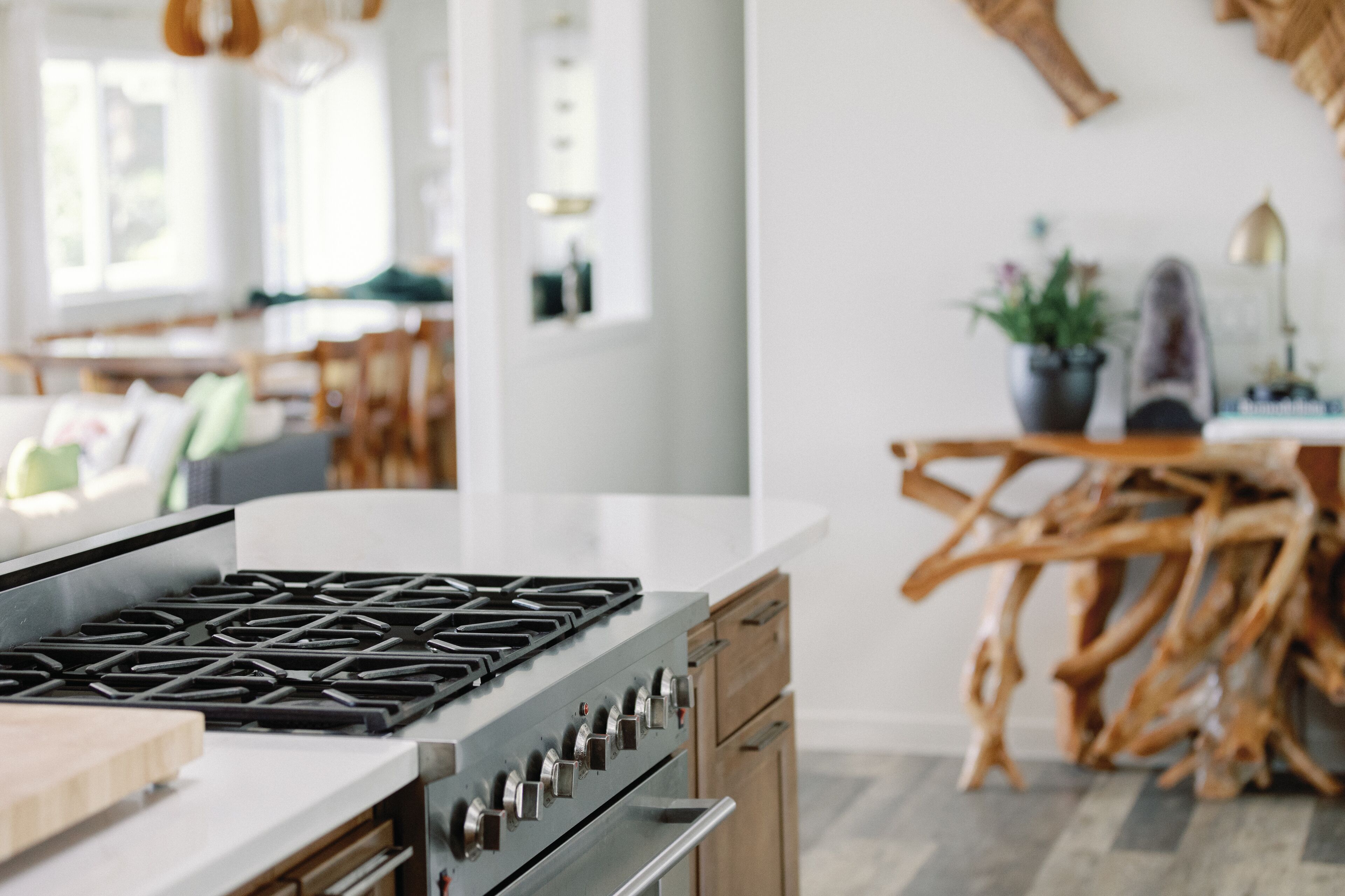 Una cocina moderna con estufa a gas, armarios de madera y un comedor con mesa y sillas de madera.