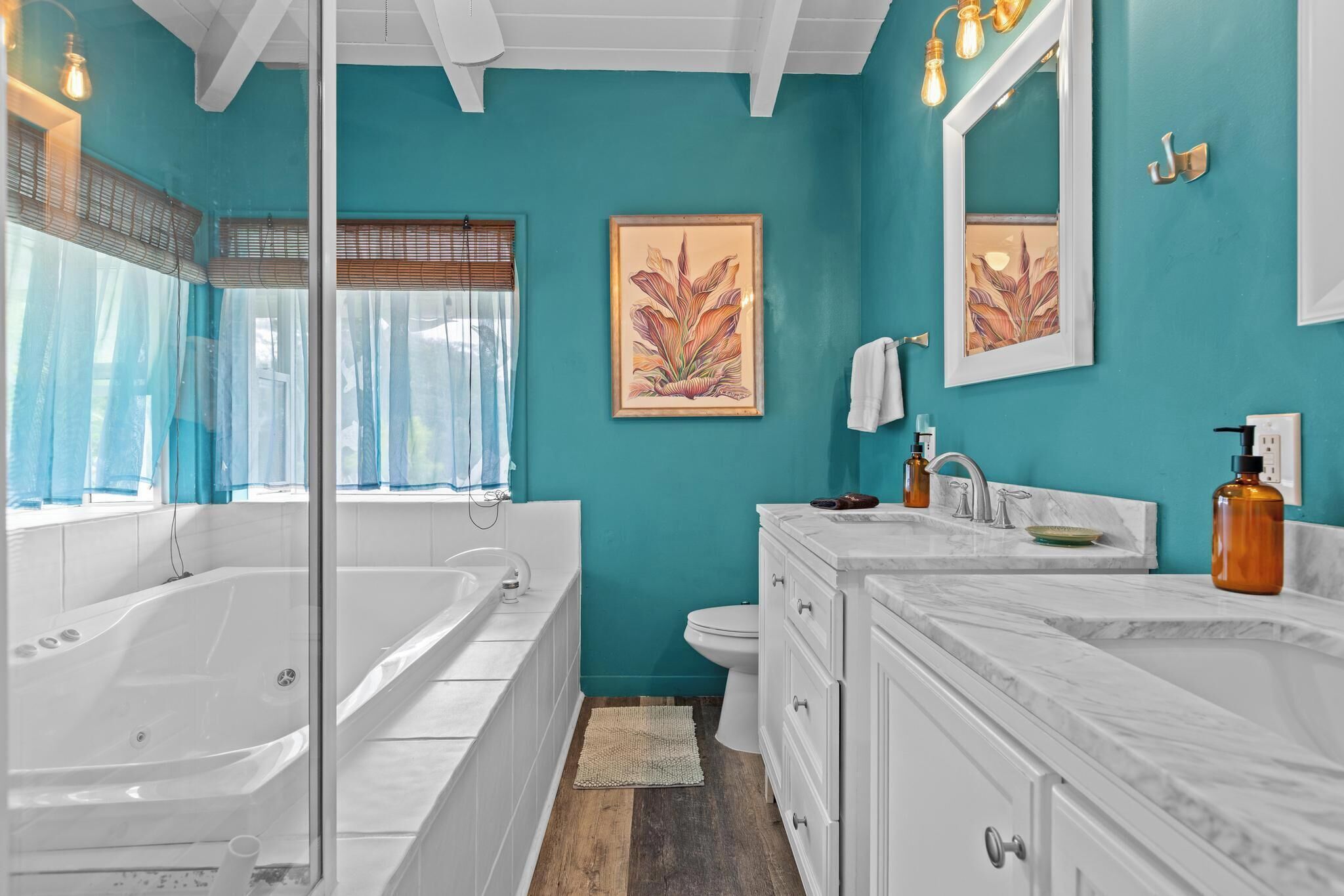 A bathroom with a large bathtub, a toilet, a sink, and a mirror.