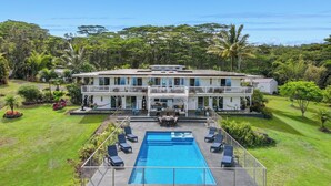 A two-story building with a swimming pool and lounge chairs.