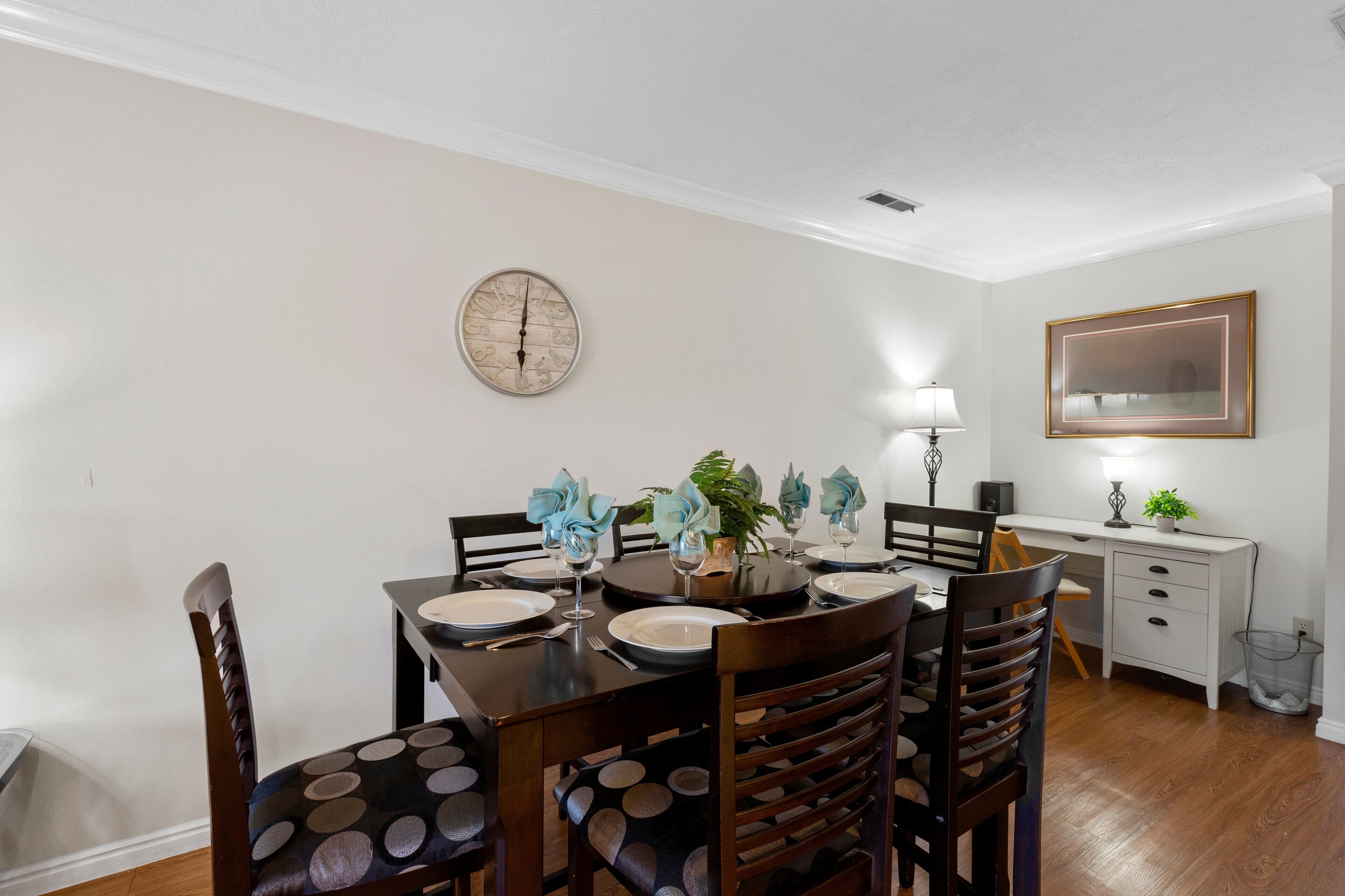 A dining area with a round table, chairs, and a clock on the wall.