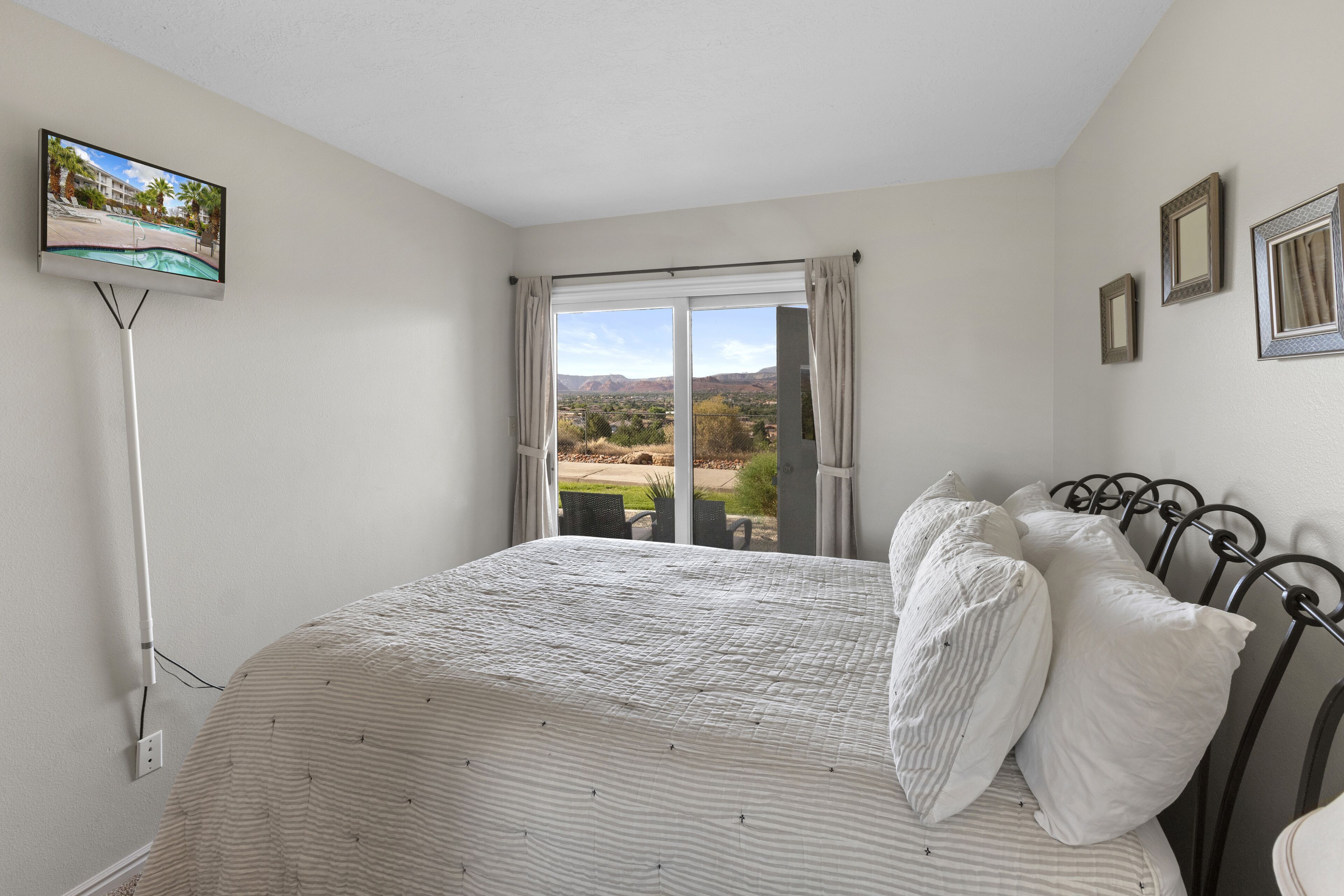 Una camera da letto con un letto, una TV a muro e una finestra con tende.
