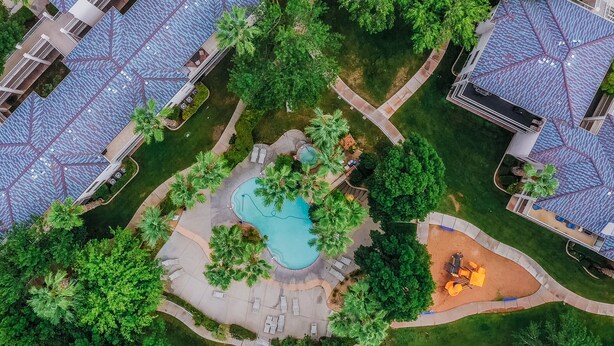 An aerial view of a residential area with a swimming pool, lounge chairs, and a small playground. - Las Palmas Resort 304, Main Level Condo, New Flooring, Mountain Views, Close to Pools, and more (St. George)