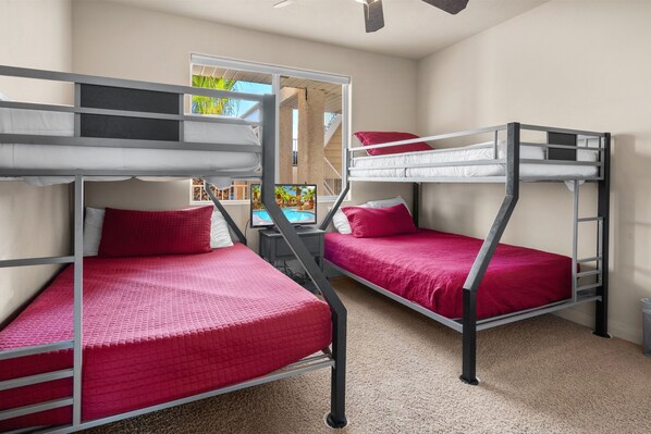 Une chambre avec un lit superposé, un téléviseur étant installé sur le lit du bas.