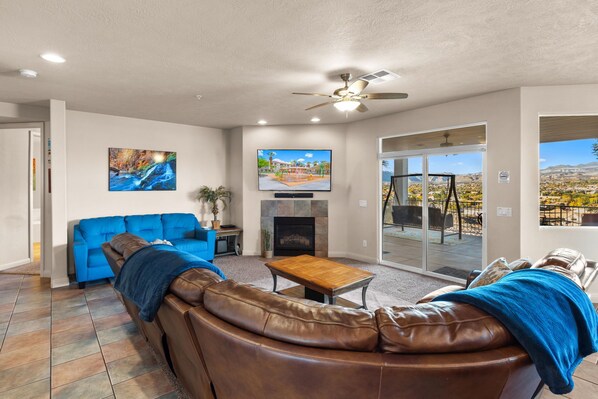 A spacious living area with a leather sofa, a blue couch, a wooden coffee table, and a fireplace. - Las Palmas Resort 806, Family Friendly, Private Balcony with Gorgeous Views, and More (St. George)