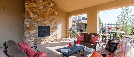 An outdoor patio area with stone walls, a fireplace, and outdoor furniture.