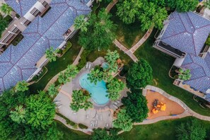 Vista aèria d'una zona residencial amb una piscina, gandules i un petit parc infantil.