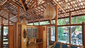 A wooden interior with a bench, hanging light fixtures, and artwork on the walls. - Pousada Casa de Praia (Mata de São João)