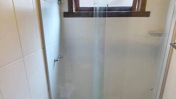 A bathroom with a glass-enclosed shower, a toilet, and a granite countertop sink.