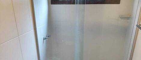 Un baño con ducha envuelta en vidrio, un inodoro y un lavamanos con encimera de granito.