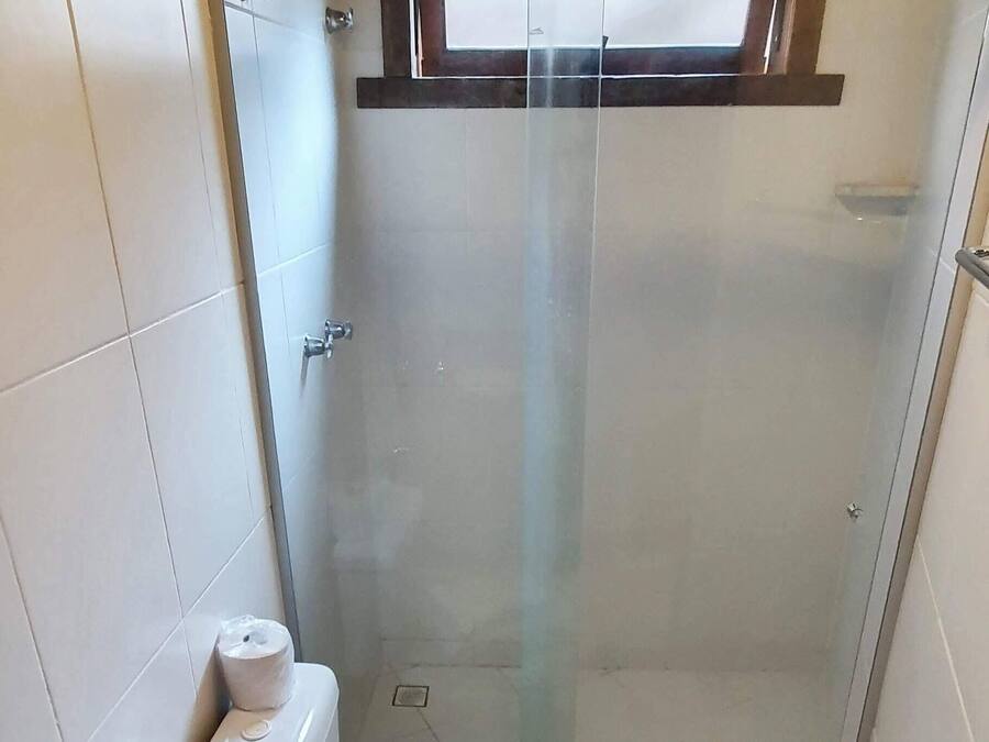 A bathroom with a glass-enclosed shower, a toilet, and a granite countertop sink.