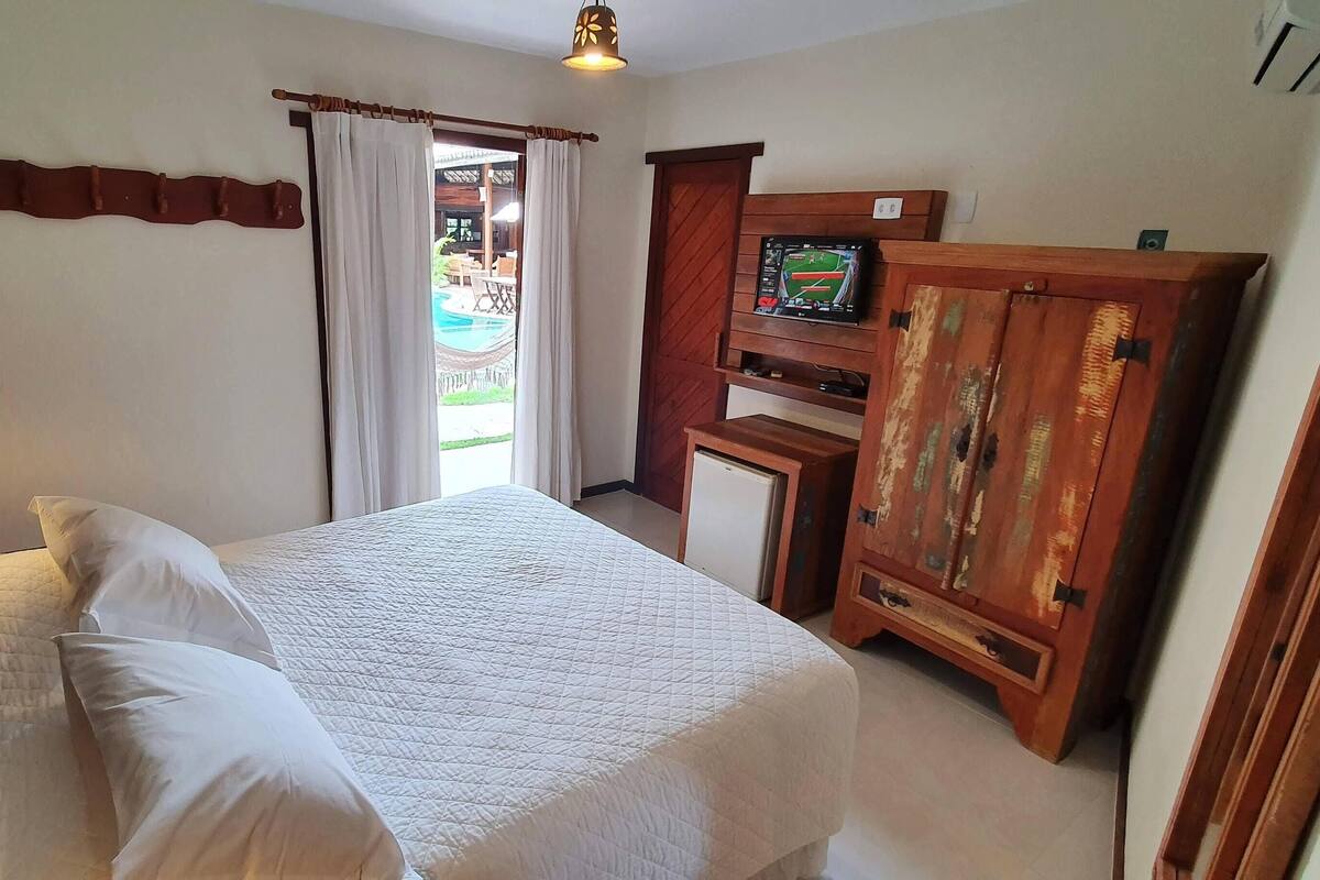 Ein Schlafzimmer mit Bett, Fernseher, Kleiderschrank und Blick auf einen Außenpool.