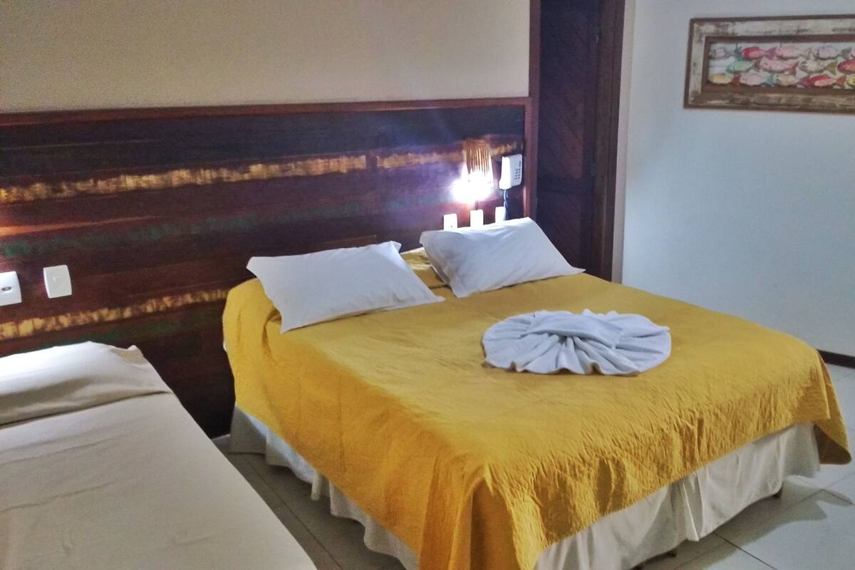 Ein Hotelzimmer mit einem Bett, einem Nachttisch, einem an der Wand montierten Telefon und einem Gemälde.