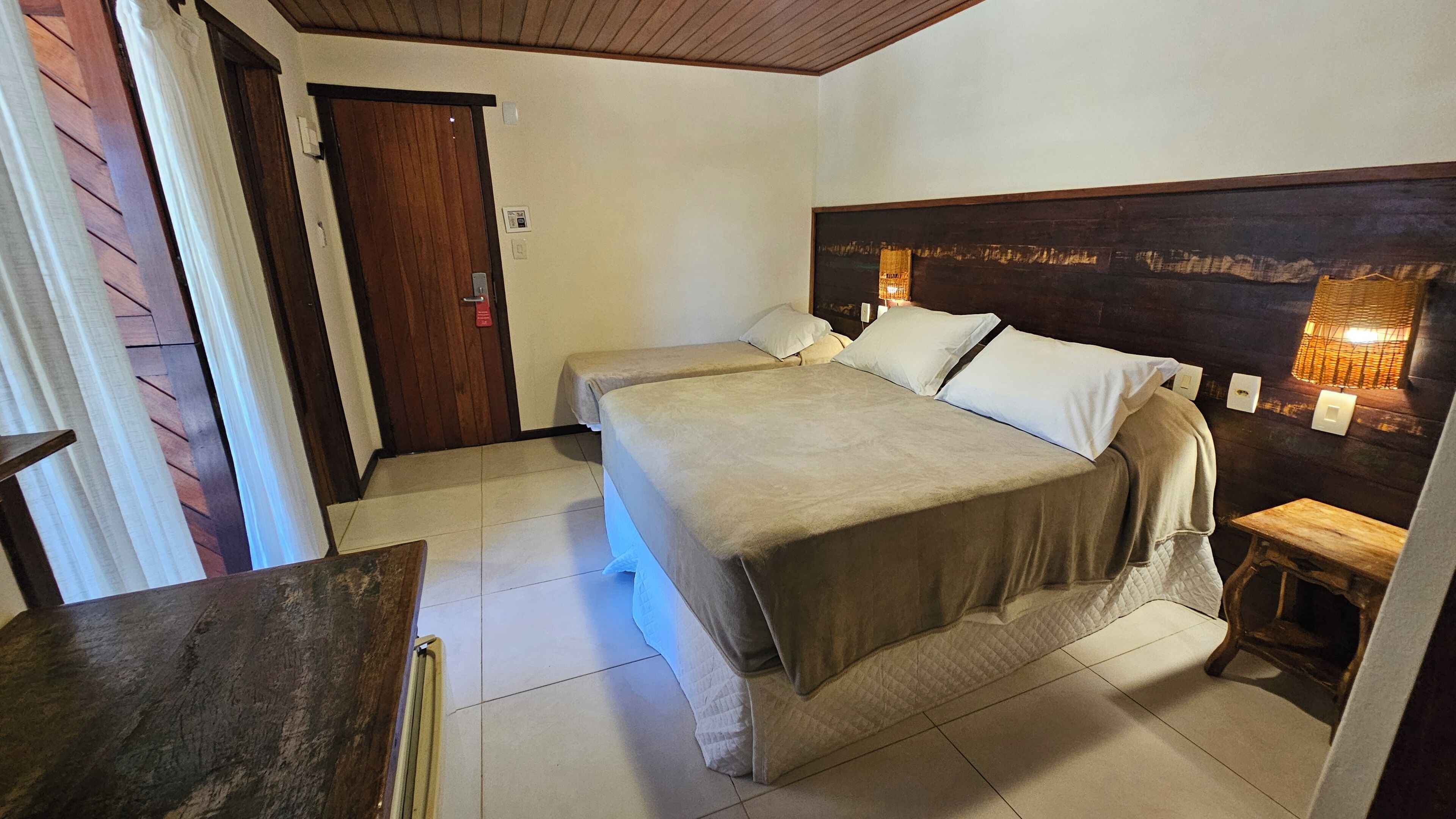 A hotel room with a large bed, a small table, and a door.