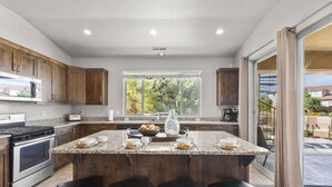 Una cocina moderna con armarios de madera oscura, encimera de granito y una isla grande con taburetes de bar.