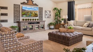 Una sala de estar con sofá, reposapiés y sillón, chimenea y televisor.