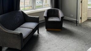 A room with a large window, a sofa, a chair, and a door. - Citi Hotel Aberdeen City Centre (Aberdeen)