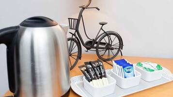 A stainless steel kettle, a bicycle, and a tray with coffee pods and a Tetra coffee box.