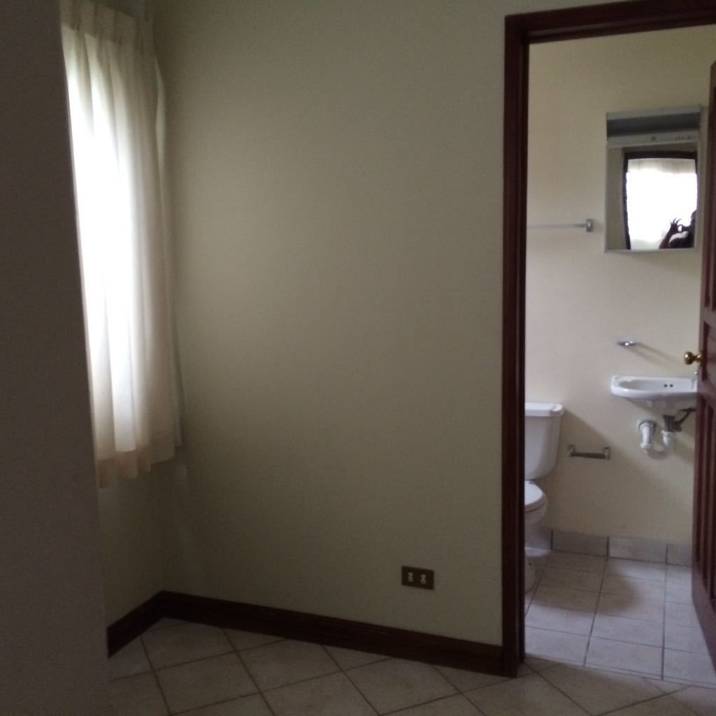 A bathroom with a toilet, sink, and mirror.