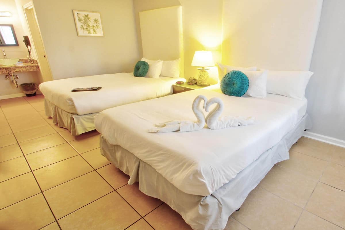 A hotel room with two beds, a bathroom, and a small sitting area.