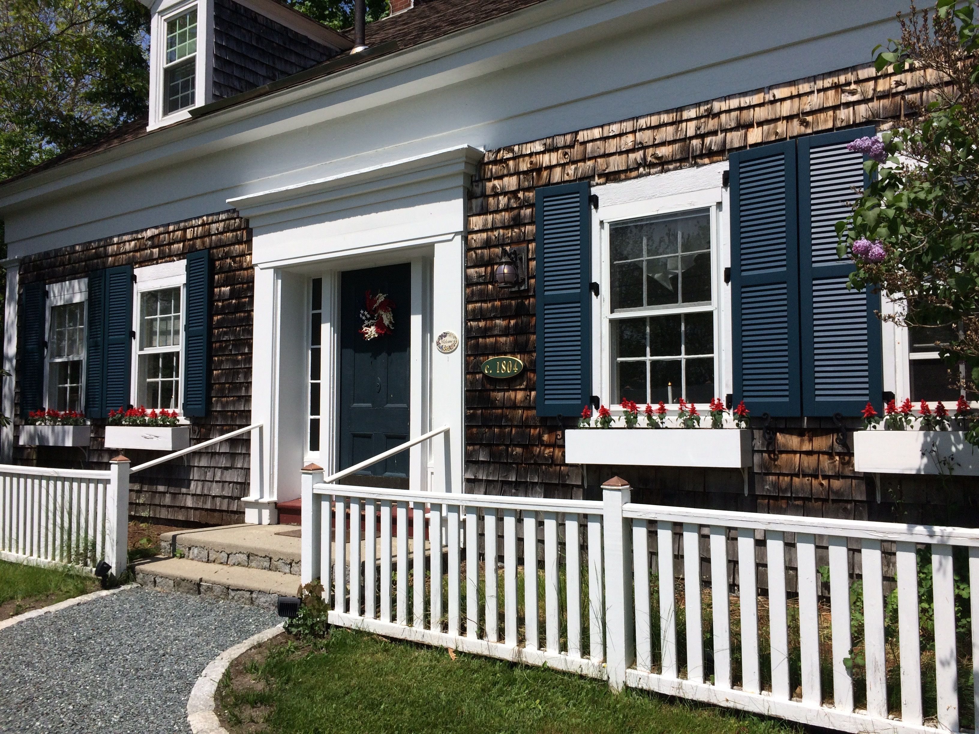 A two-story house with a front porch, a white picket fence, and a mailbox.